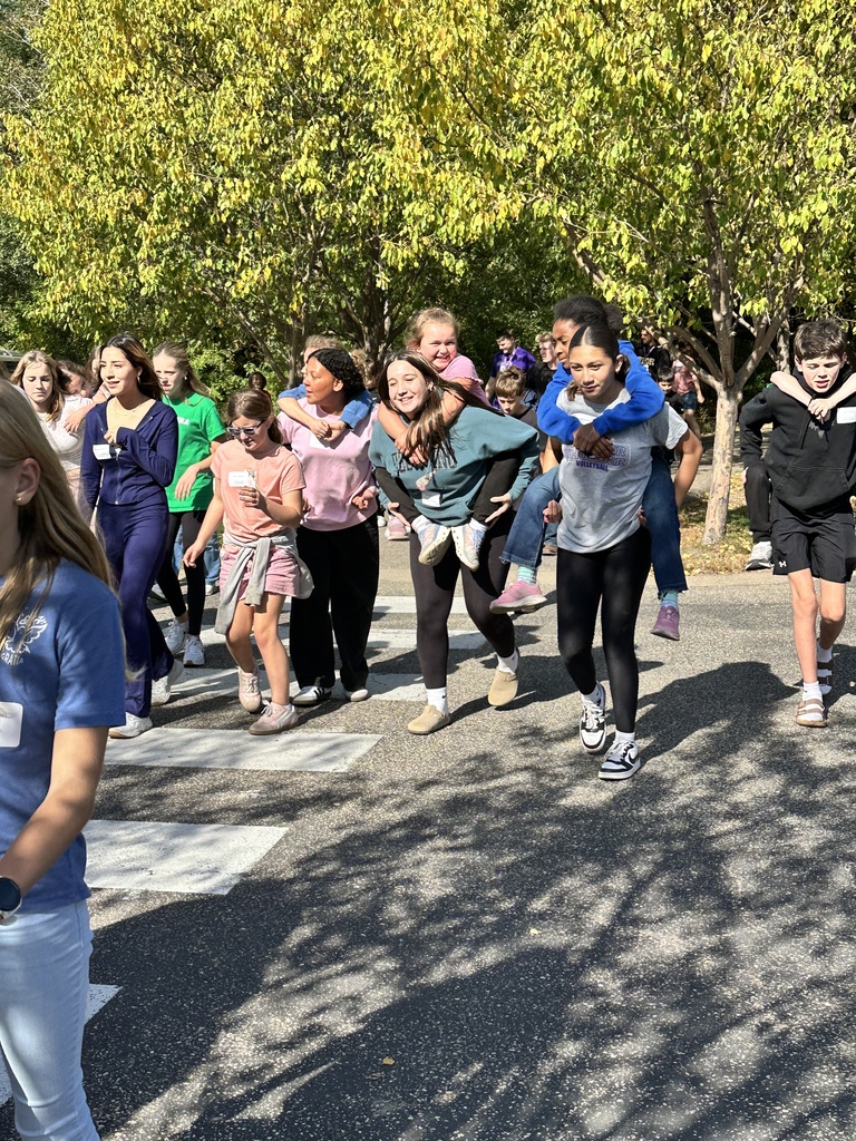 group of students walking, older students giving piggyback rides to younger students