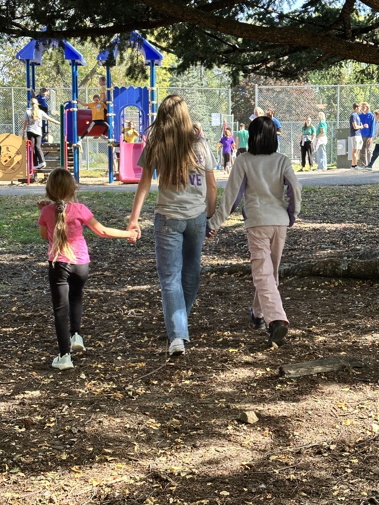 three students holding hands while walking