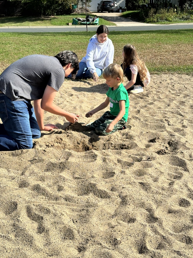 four students playing in the sand