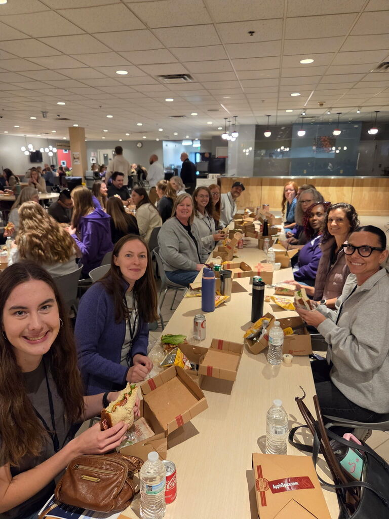 group of people seated at a long table eating lunch