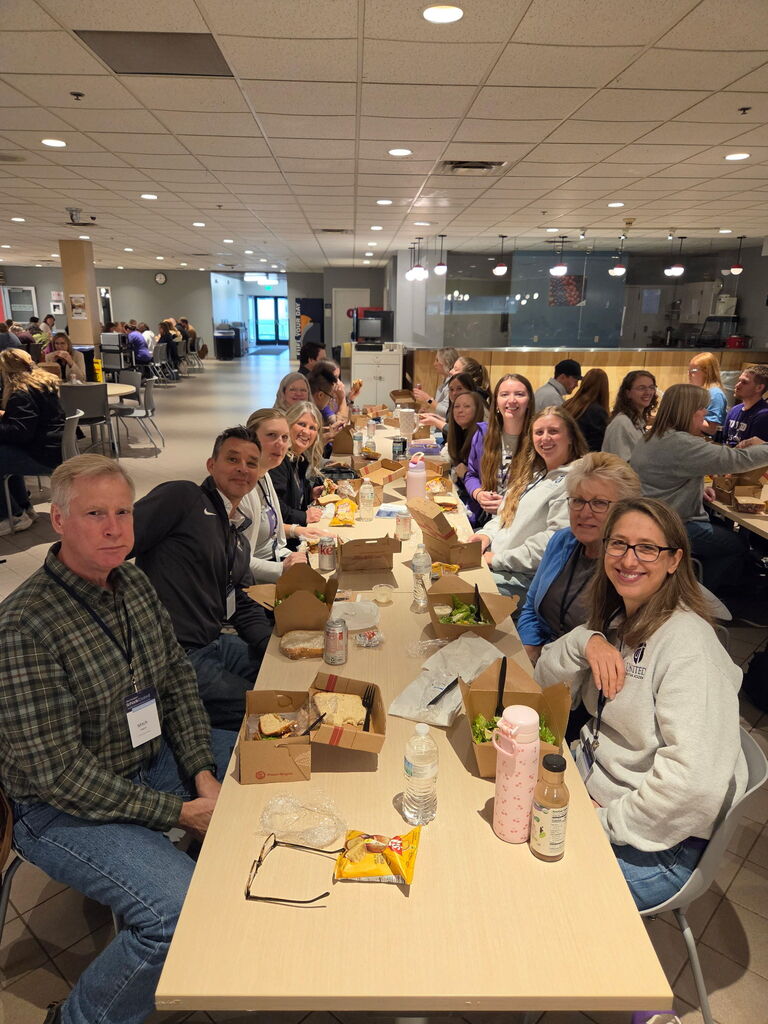 group of people seated at a long table eating lunch