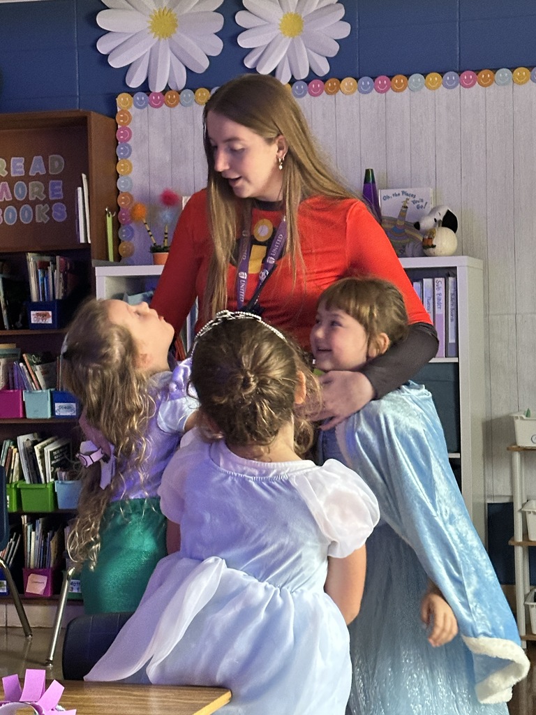 three students hugging their teacher