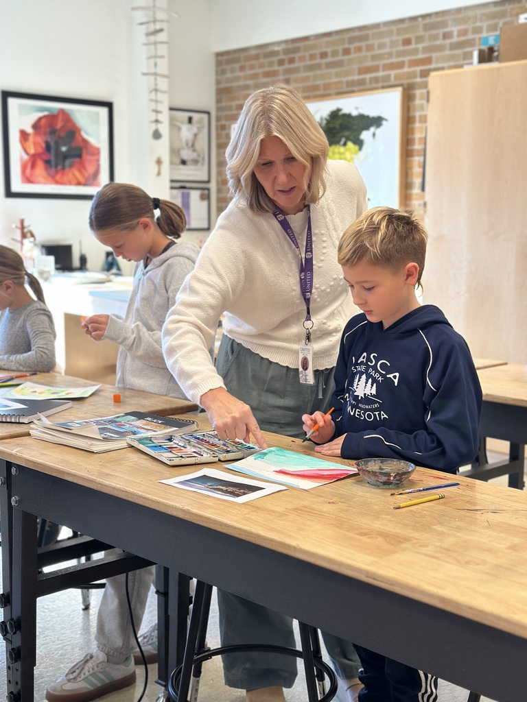 teacher helping a student at his desk with an art project