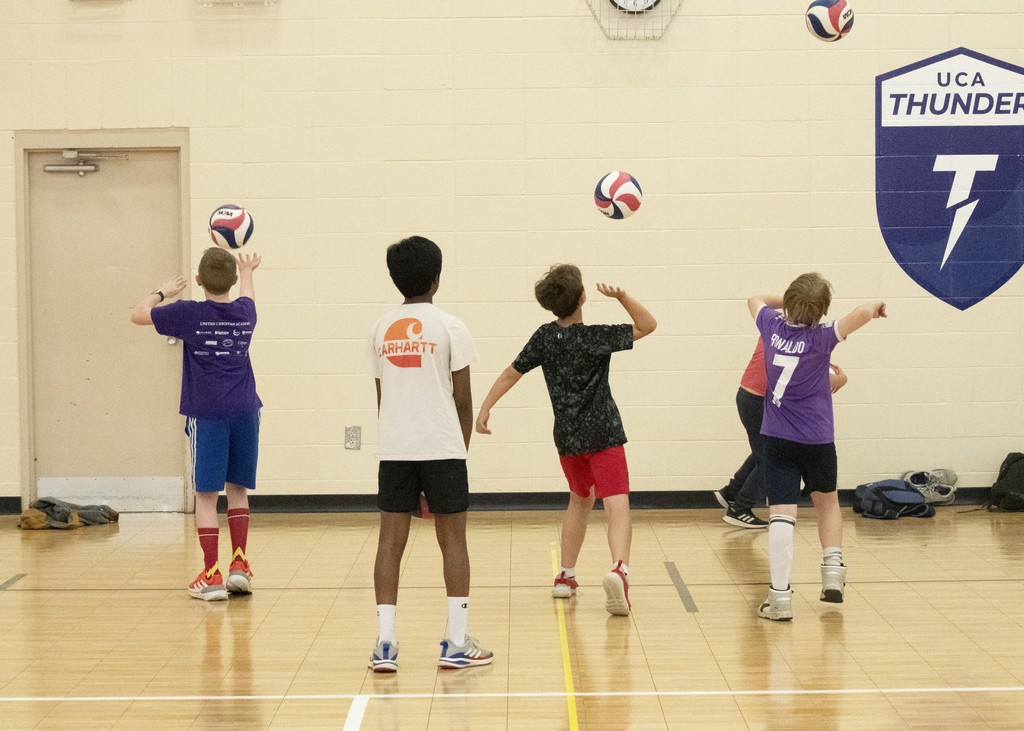high school volleyball player helping a younger student