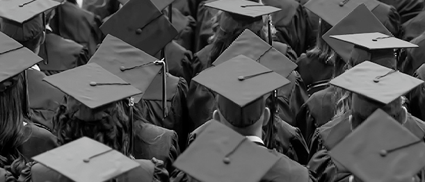 Image of graduates highlighting caps, tassles, and gowns. Image is taken from behind.