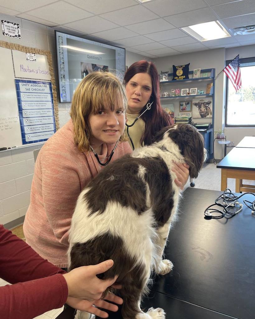a picture of a student, and educational assistant, and a dog 