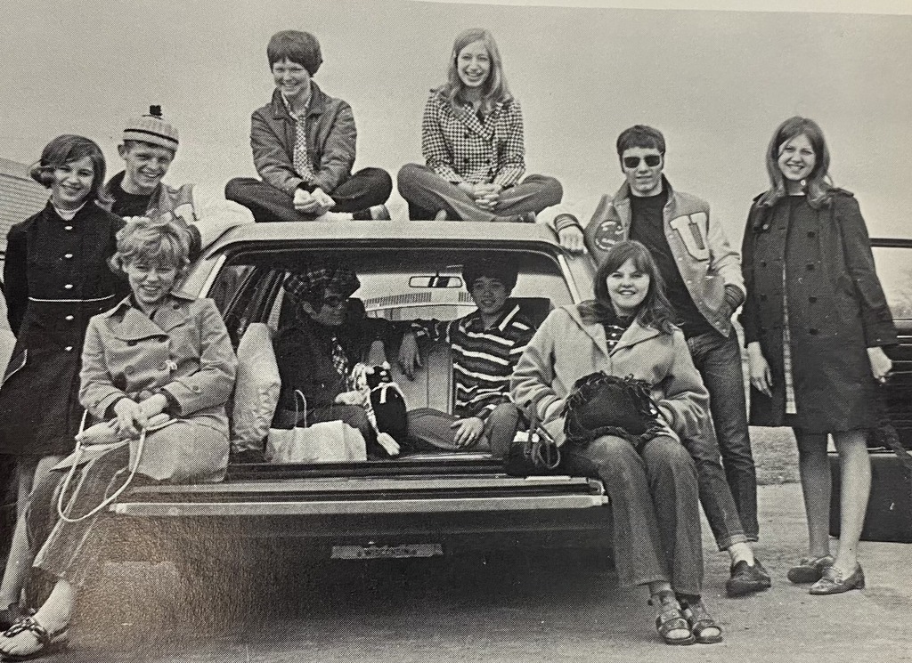 black and white picture 10 students from the 1970's by a station wagon car