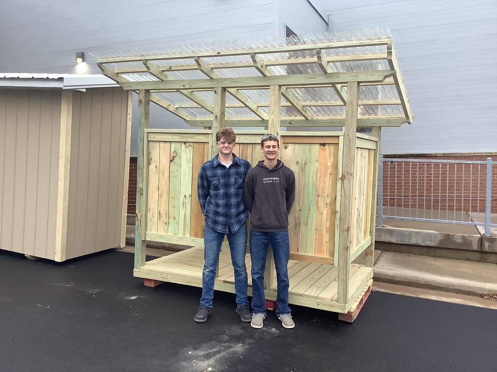 picture of two students standing in front of a structure they built