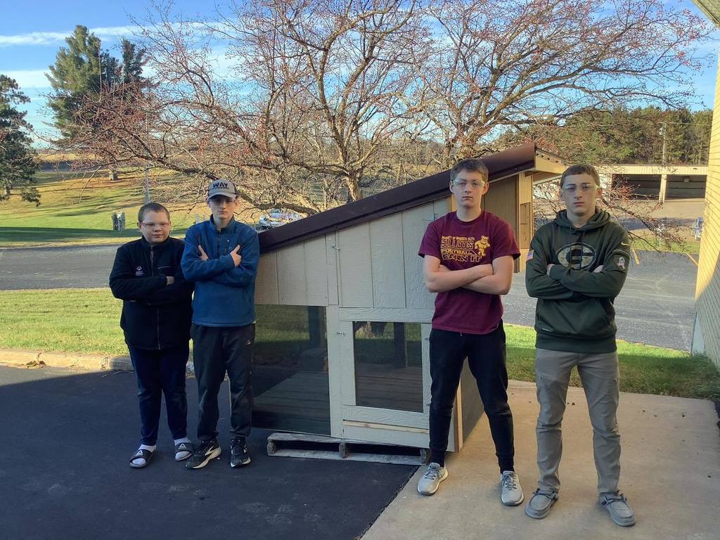 picture of four students standing in front of a structure they built