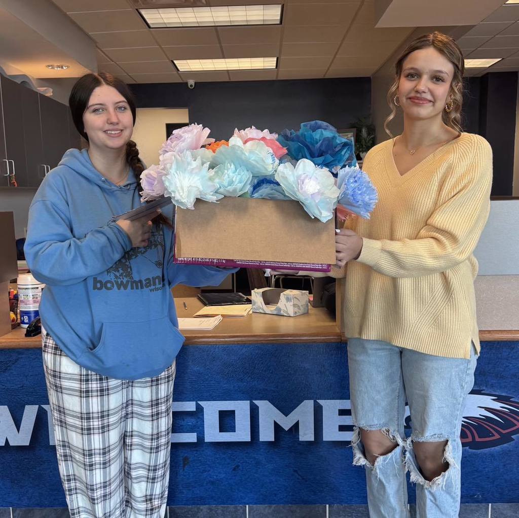 picture of two students holding a box of paper flowers