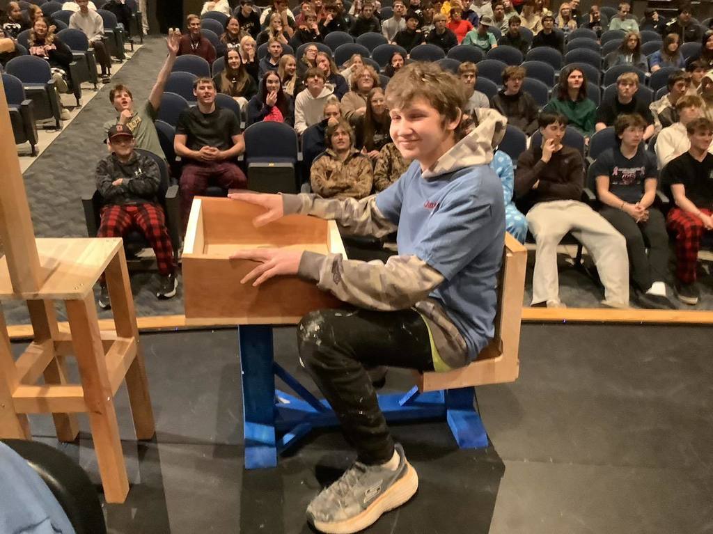 picture of student sitting in a desk on stage in the PAC