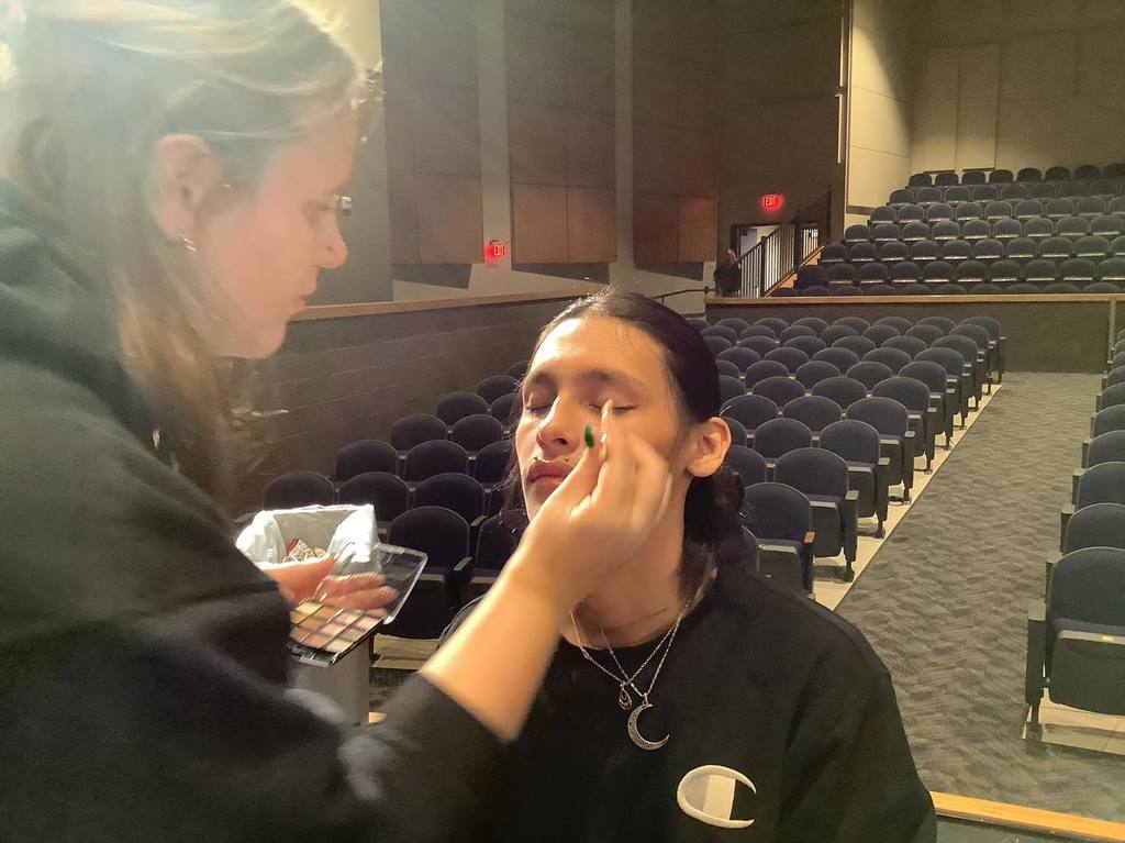 picture of student applying face makeup to another student's face