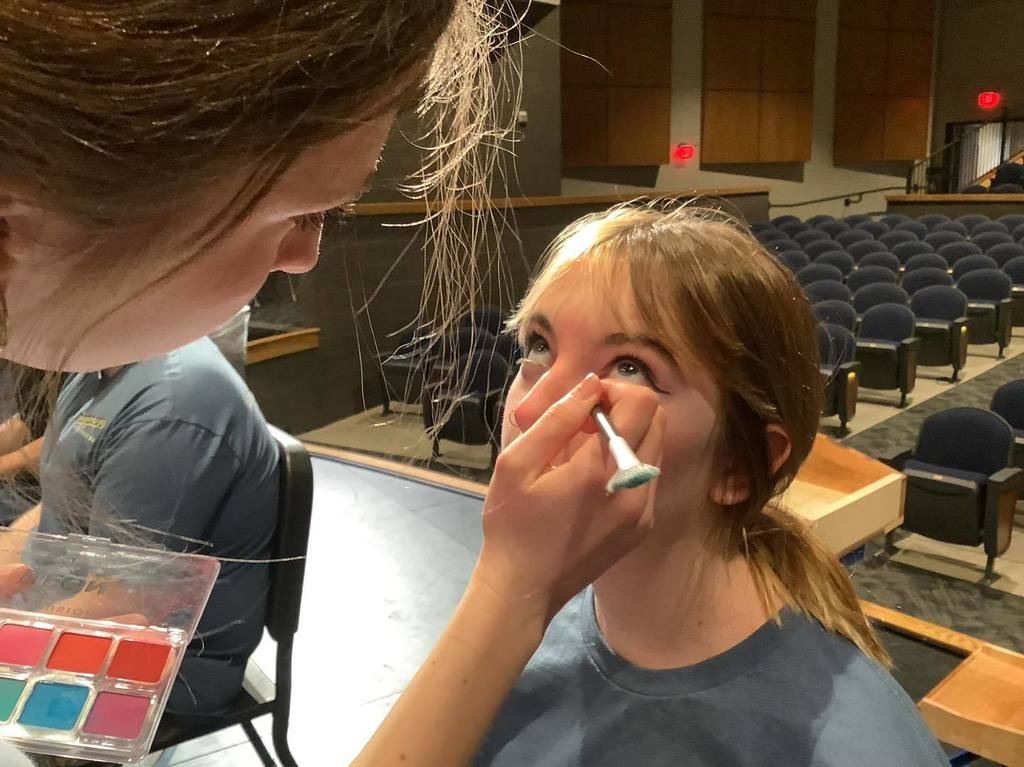 picture of student applying face makeup to another student's face