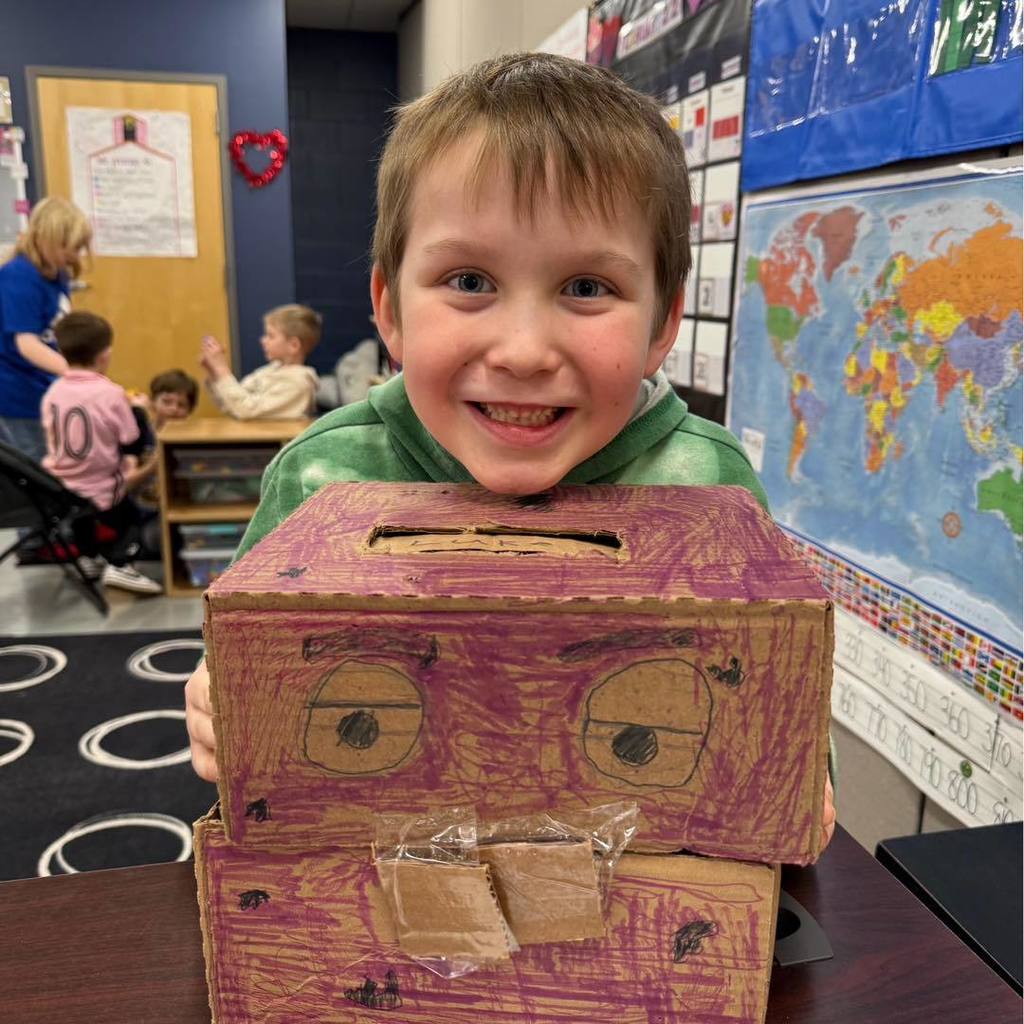 picture of  A smiling student holding a purple and brown handmade Valentine's Day box designed to look like a robot