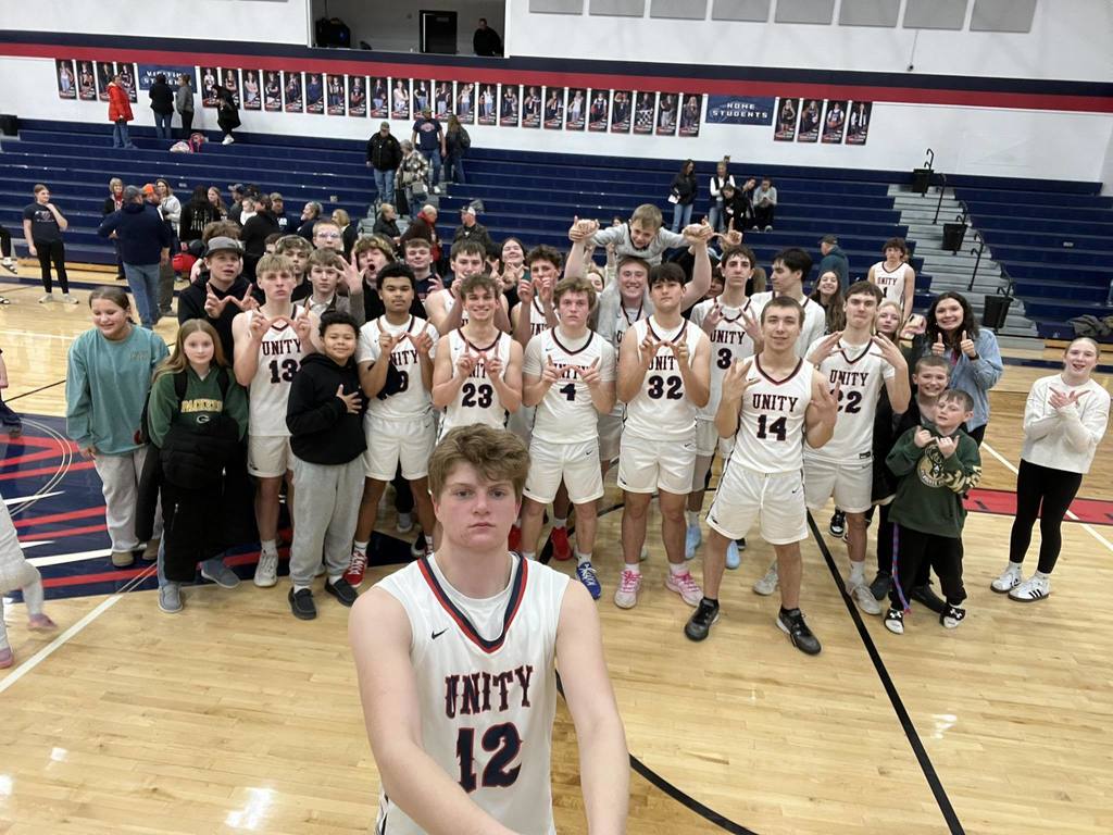 The Unity Boys Basketball team posing for a group photo on the court with students and supporters after their victory against Ladysmith on Senior Night.