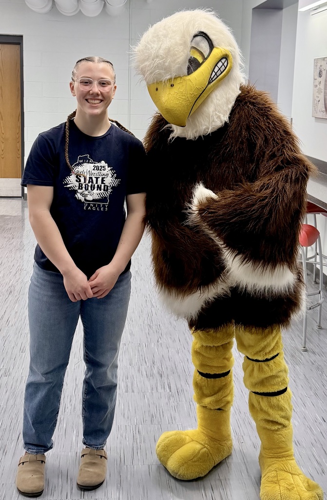 Evelyn Fugate standing and smiling next to the Unity eagle mascot in a school hallway.