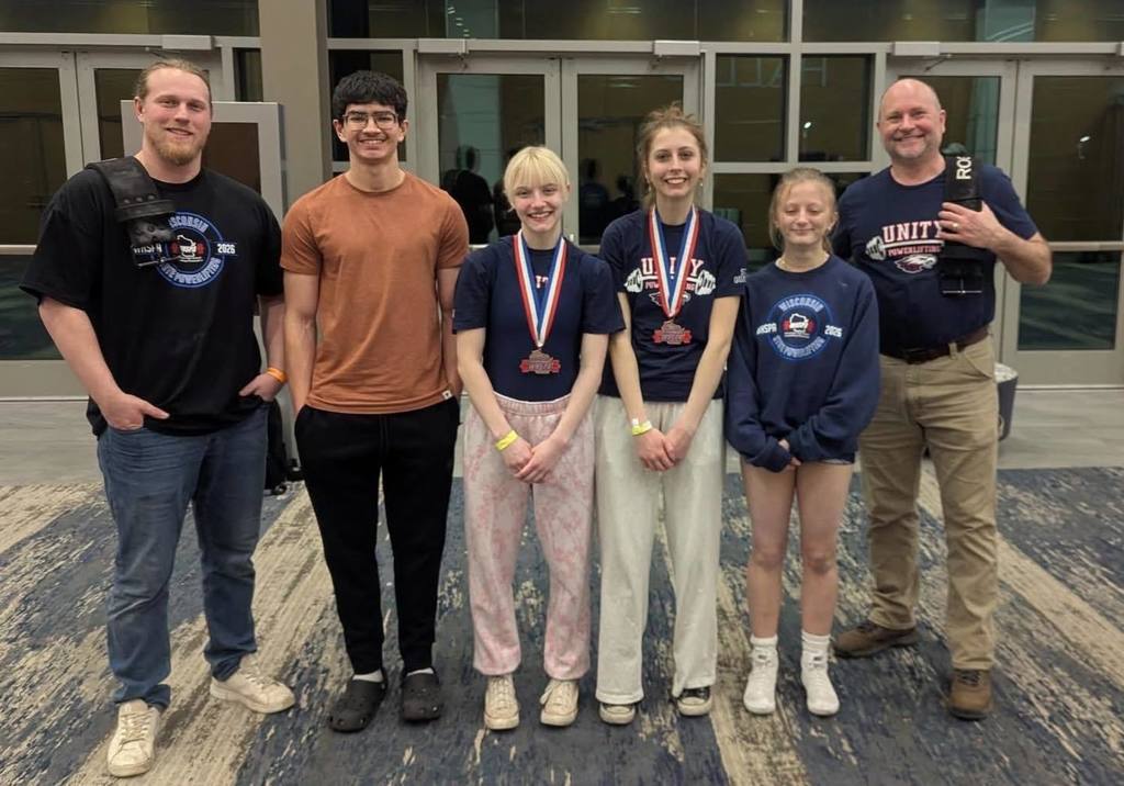 For the first photo in the gallery (the group of six standing in the hallway), here is the alt text: "Five Unity Powerlifting students and their coach standing together in a hallway. Two of the students are wearing their State medals around their necks, and the coach is wearing a 'Unity Powerlifting' t-shirt. They are all smiling and celebrating their performance at the State meet.