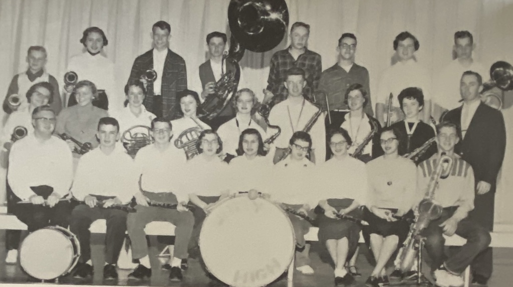 A vintage black-and-white group photo of a school band or choir from the past, featuring students in rows with their instruments, including a large bass drum in the center.