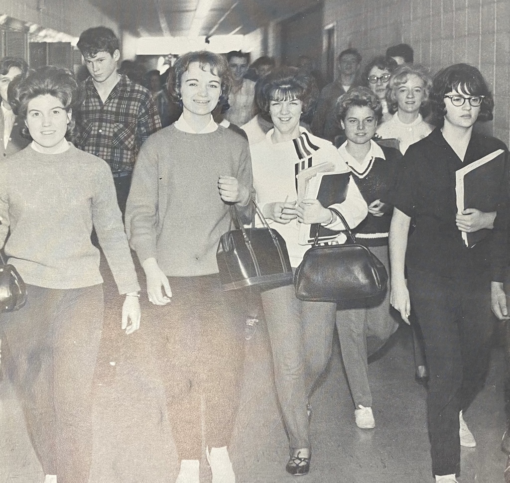 A group of students in the 1960s walking through a school hallway, featured in a vintage Unity School District yearbook.