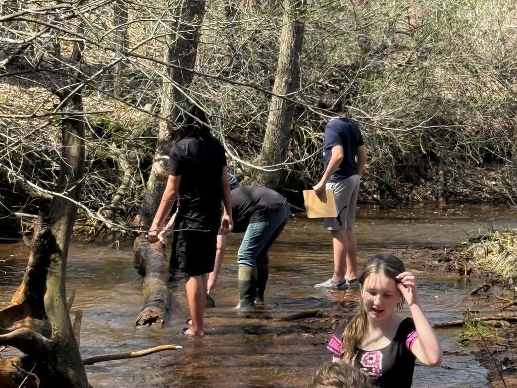 Unity 7th graders participating in an Earth Day stream survey at Rice Creek, wading into the water to collect and index macro-invertebrates.