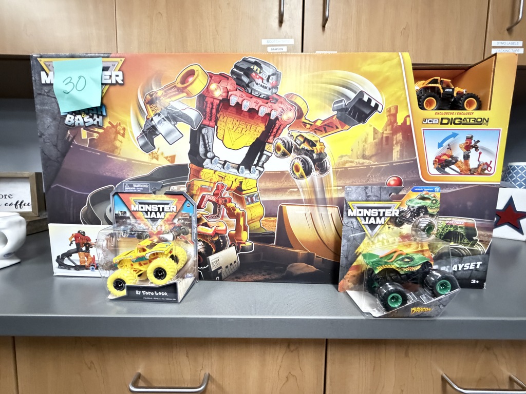 Boxed Monster Jam Dirt Arena playset featuring a large mechanical creature, displayed alongside small die-cast Monster Jam trucks including El Toro Loco and Digatron, marked with a number 30 tag.