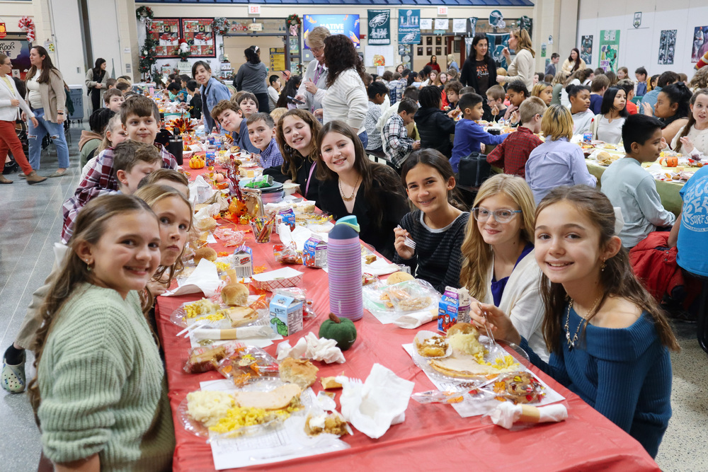 Children enjoying a meal at a long table with autumn-themed decorations.