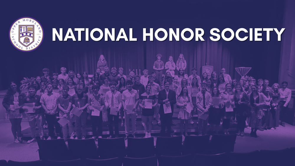 A group of students on stage holding certificates at a National Honor Society event.