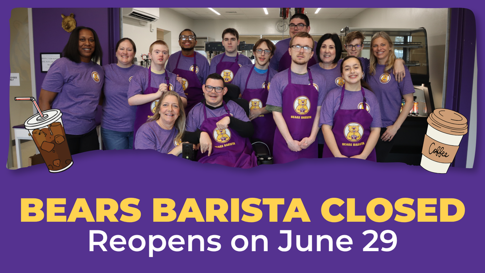 Group photo of Bears Barista staff wearing purple shirts and aprons with cafe in the background.