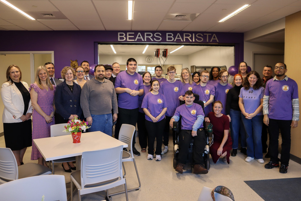 Students, staff, and school board members smile and pose in front of the Bears Barista