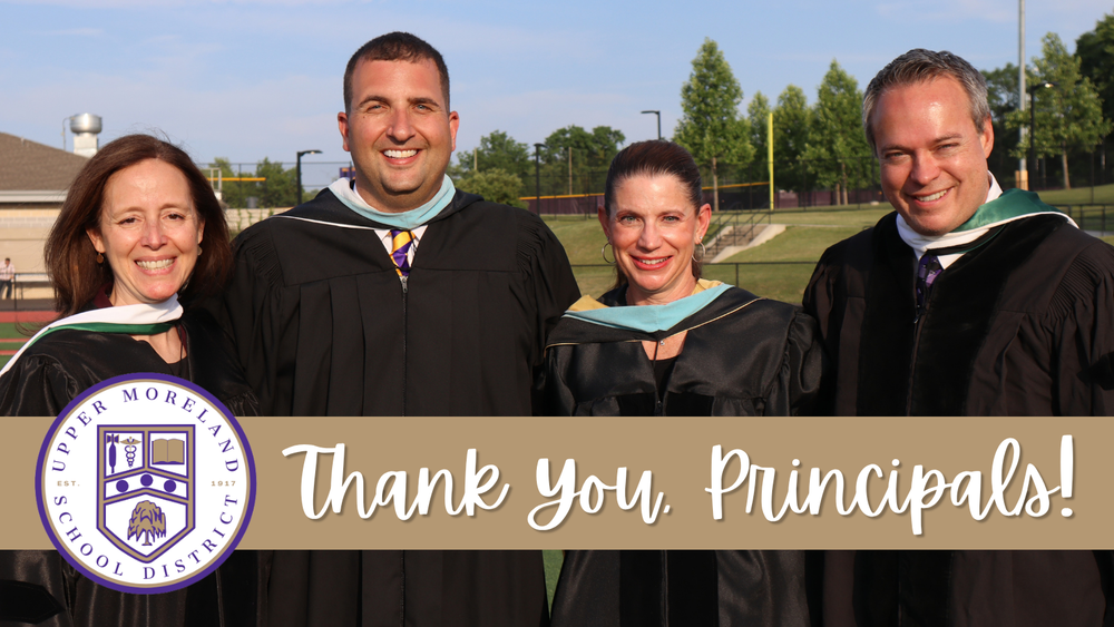 Four adults in academic robes smile in front of a sports field beneath a banner reading “Thank You, Principals!”