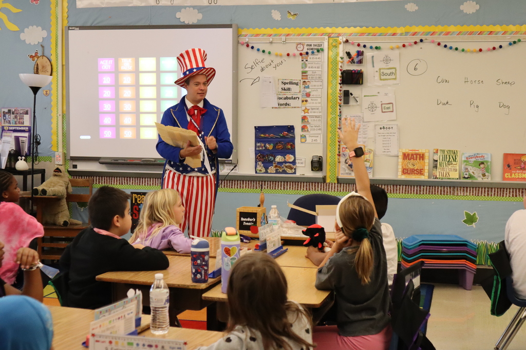 Dr. Bair dressed up as Uncle Sam talks to students about the Constitution in a classroom. A student is raising their hand.