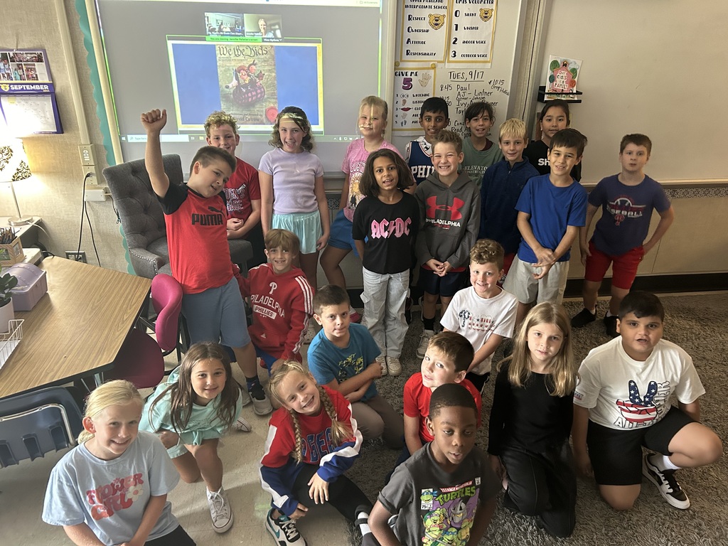 Group of 4th-grade students standing in front of a picture of the book 'We the Kids' smiling