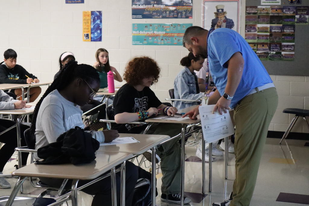 Teacher assists an 8th grade student with their worksheet.