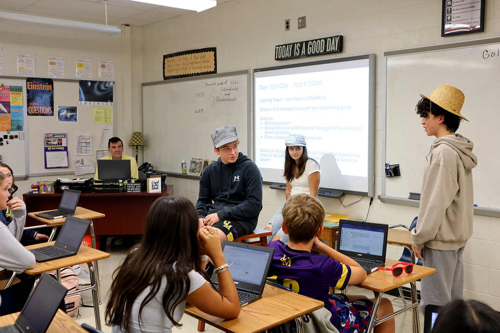 Three students performing their skit at the front of the classroom in front of classmates