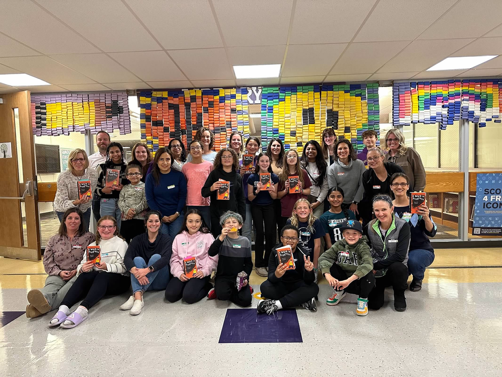 Full group of Book Club members smiling and holding up copies of their books