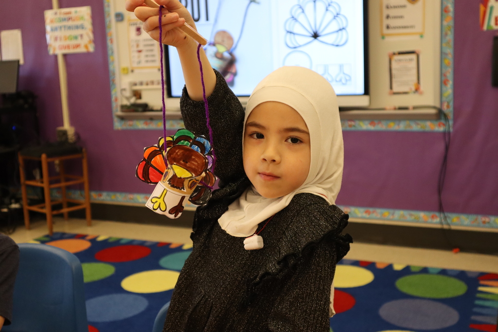 Student holding up their turkey marionette