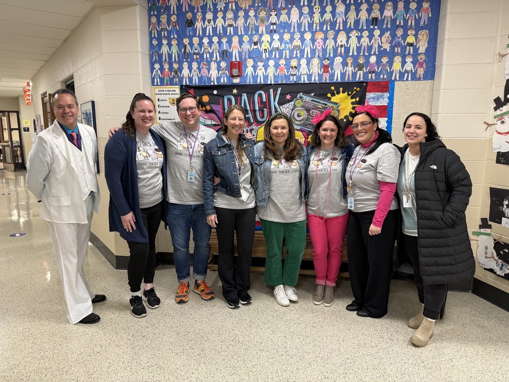 Teachers smiling. Some dressed in 80s fashion and some wearing 100 days of school shirt