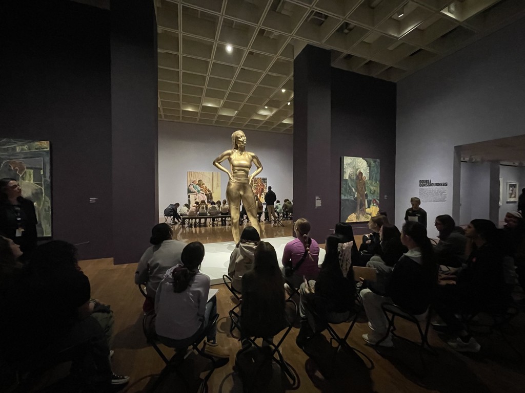 Students listening to the art educator discuss a piece