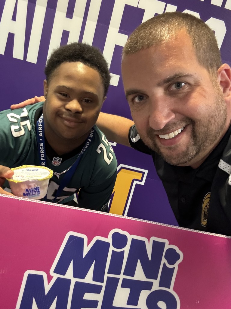 UMHS Principal and a student smile for a photo in front of a Mini Melts Ice Cream sign