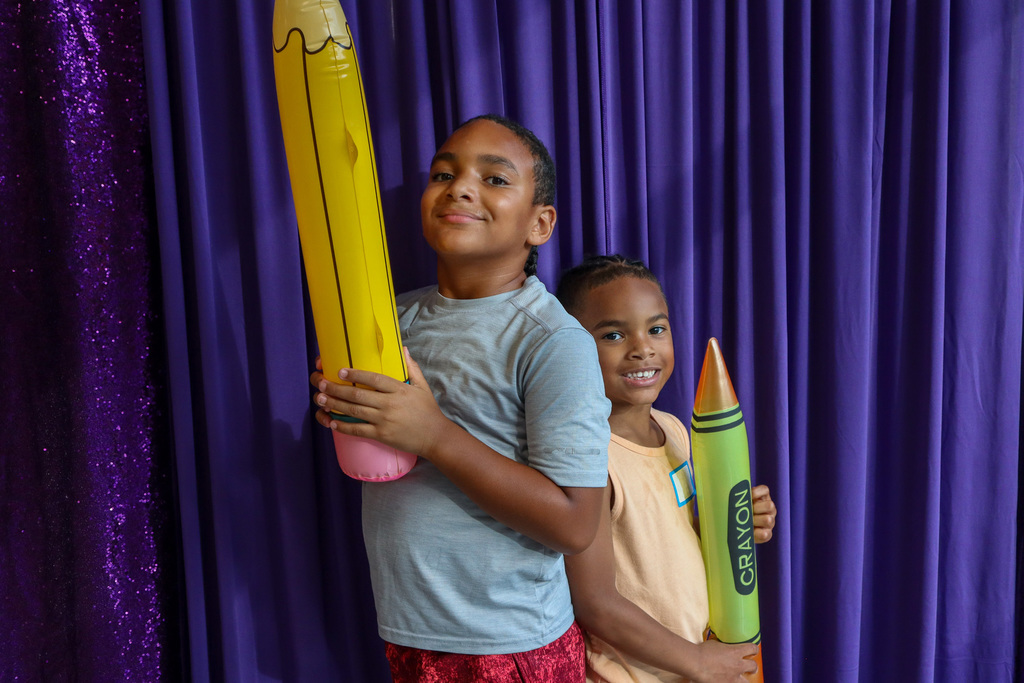 Two boys posing with a pencil and crayon inflatable