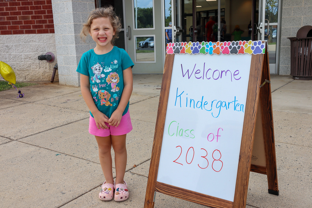 Student posing next to 'Welcome to Kindergarten' sign