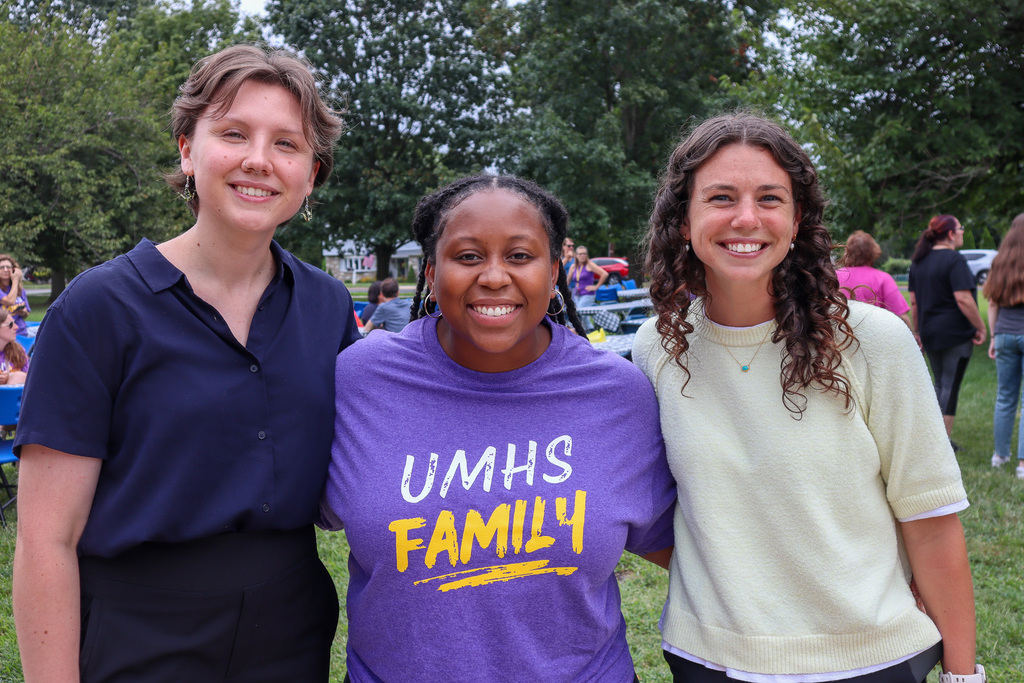 Three staff members smile and pose for a photo