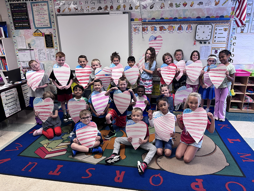 Students smile in a group and hold their Patriotic craft