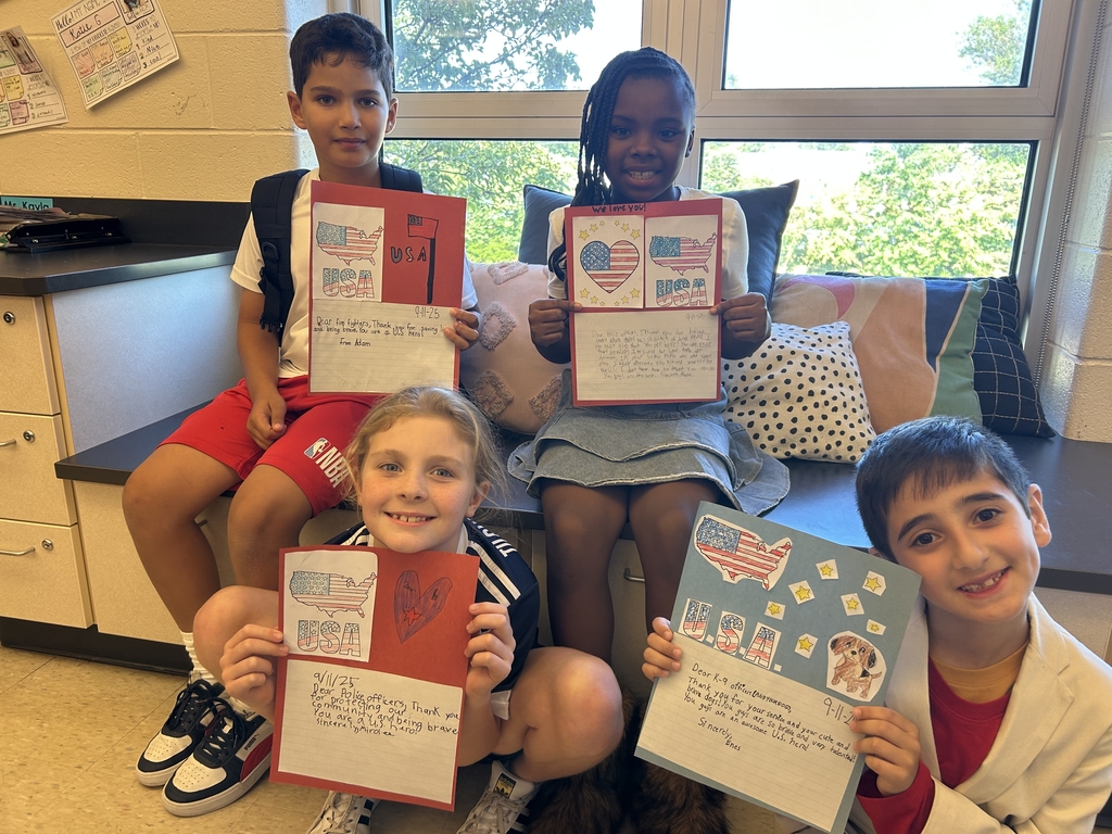 Students smile in a group and hold their Patriotic craft