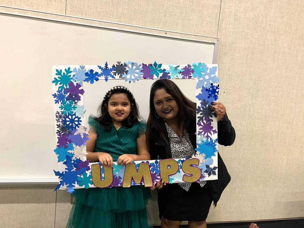 Student and parent pose in front of a UMPS frame