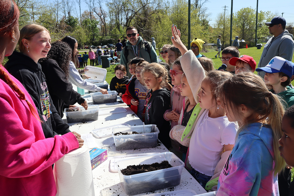 2nd-graders raising their hands at a science station