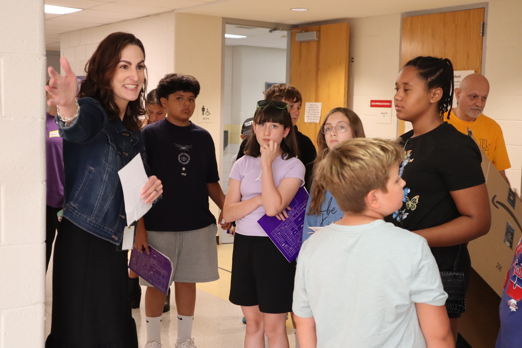 Staff member leading a tour to a group of 6th graders in the hallway