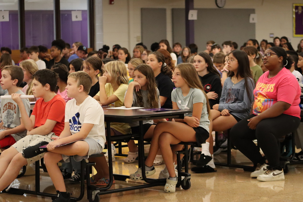 Group of 6th grade students listening to a presentation in the cafeteria