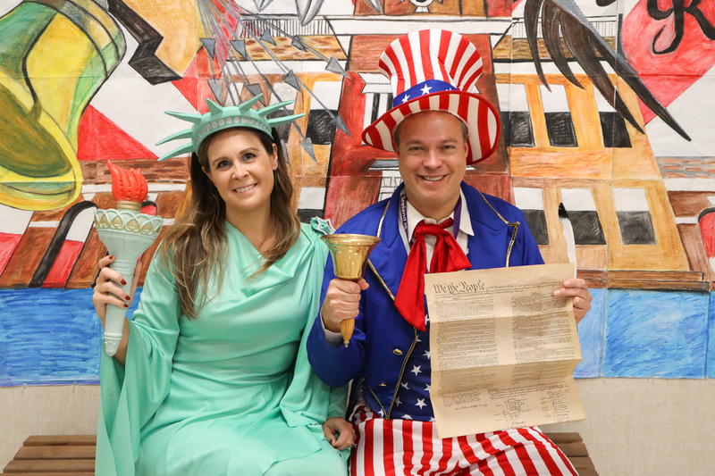 UMIS Principals dressed as Uncle Sam and Lady Liberty, posing with a copy of the Constitution