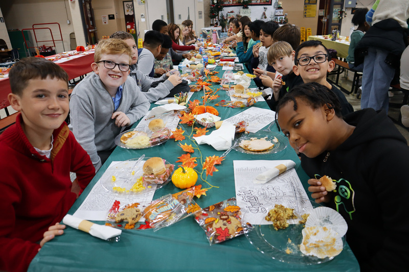 Children enjoying a meal at a long table with autumn-themed decorations.